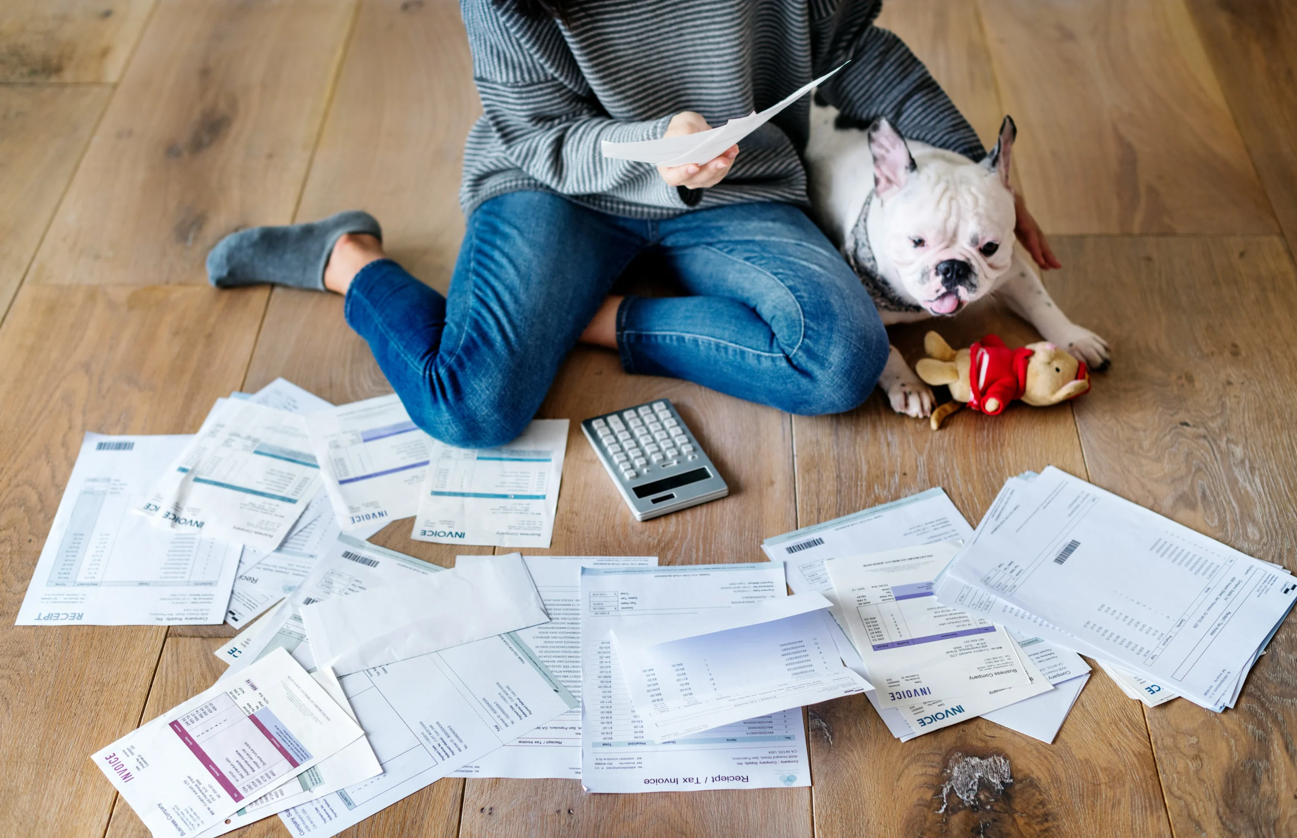 woman on floor with her dog while surrounded by student loan invoices