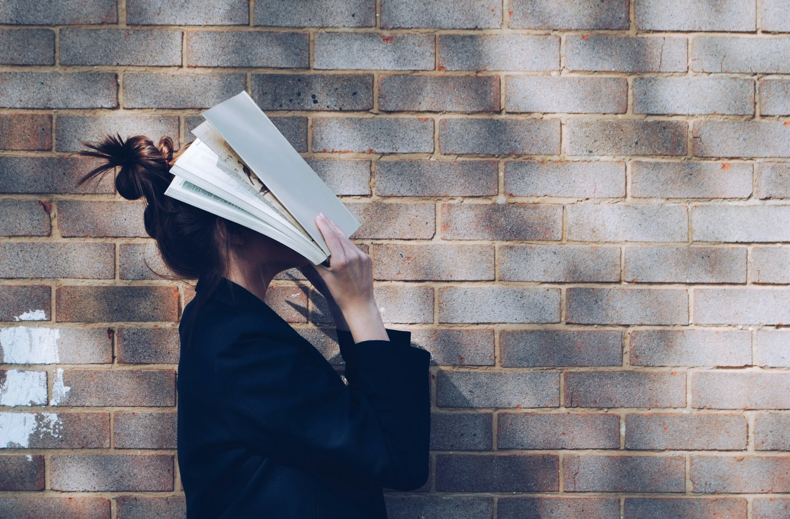 student hiding her face in an open book